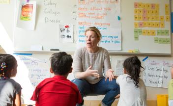 Elementary teacher explaining social studies lesson to group of kids in classroom