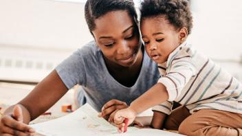 Young mother with toddler child drawing with a crayon