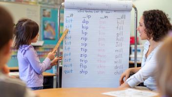 First grader at board reading 3-letter words for teacher
