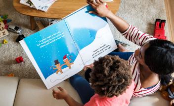 Birds-eye view of mother at home reading picture book to young child