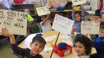 Elementary kids holding up word study examples in class