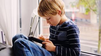 Young boy a home on couch using a phone app