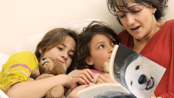 Mother reading book about polar bears to her two kids