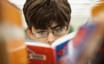 Elementary school boy choosing graphic novel from library shelf