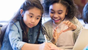 two elementary girls talking about an assignment in class