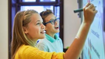 two elementary school students working on assignment on whiteboard