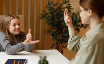 Elementary school-aged deaf student using sign language with teacher