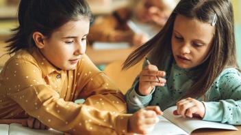 two elementary students reading the beginning of a book together