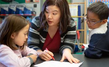Elementary teacher working with two students on reading