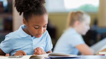 Young girl reading book in class during silent reading time