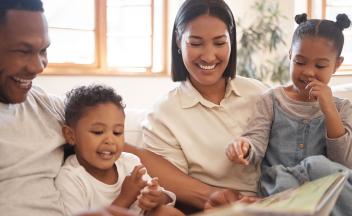 Parents reading picture book to their two young children