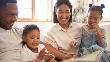Parents reading picture book to their two young children