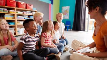 Woman sharing a read aloud with a diverse group of kids