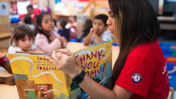 Volunteer reader doing a picture book read aloud with diverse group of kids