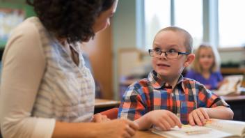 first grade student practicing reading with teacher