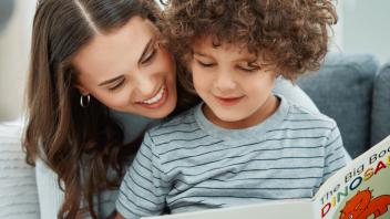 Mother reading book about dinosaurs to young son