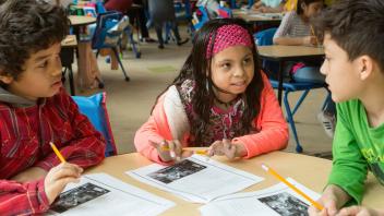three elementary students working on writing together