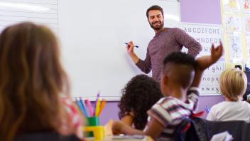 male elementary teacher at whiteboard with class